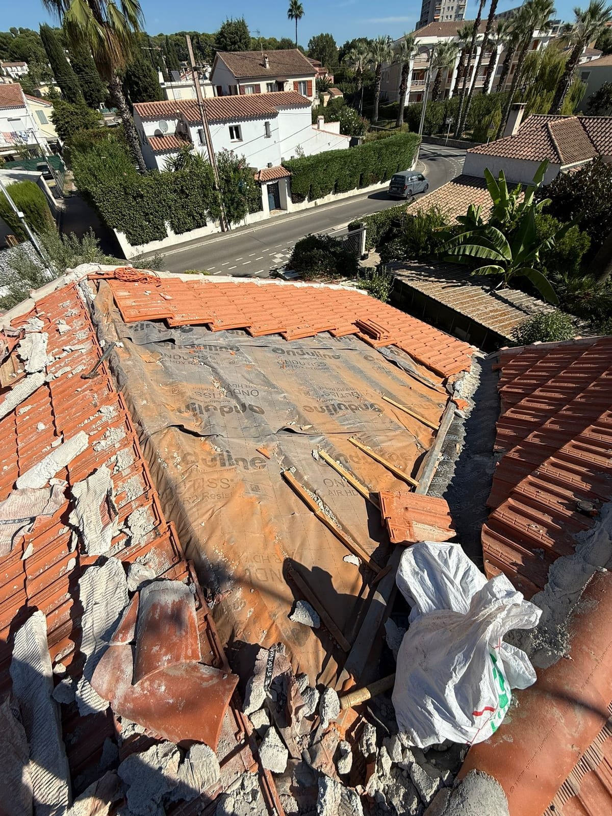Écran de sous-toiture déroulé sur un versant, tuiles reposées rang par rang depuis l'égout