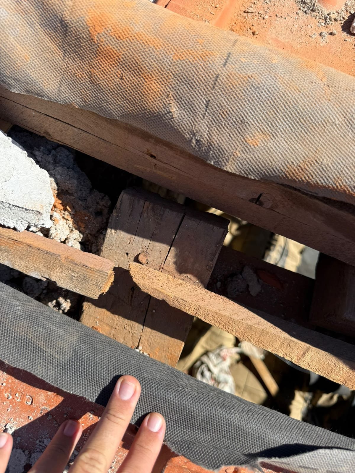 Gros plan sur un liteau rompu et un chevron ancien fendu, sous l'écran de sous-toiture d'une toiture ouverte